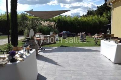 Décoration champêtre avec canapé, fauteuils, bottes de paille et guirlandes dans un jardin verdoyant.