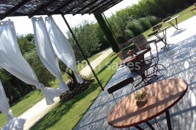 Décoration champêtre avec canapé, fauteuils, bottes de paille et guirlandes dans un jardin verdoyant.