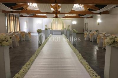 Décoration champêtre avec canapé, fauteuils, bottes de paille et guirlandes dans un jardin verdoyant.