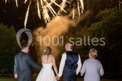 Un couple en tenue de mariage s'embrasse dans un jardin, avec des arbres en arrière-plan.