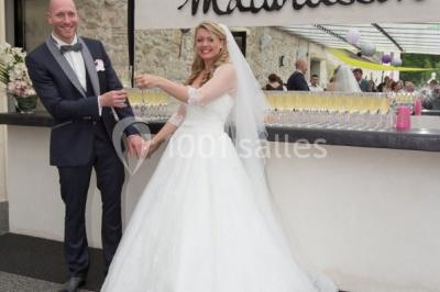 Un couple en tenue de mariage s'embrasse dans un jardin, avec des arbres en arrière-plan.