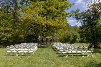 Un couple en tenue de mariage s'embrasse dans un jardin, avec des arbres en arrière-plan.
