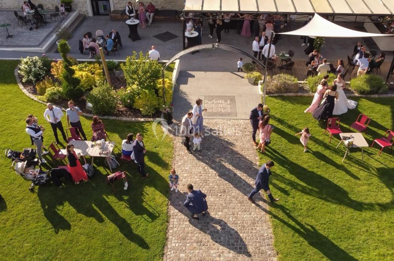 Vue aérienne d'un jardin avec des invités rassemblés lors d'un événement en plein air près d'une terrasse aménagée.