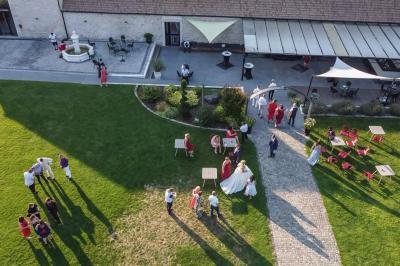 Un couple en tenue de mariage s'embrasse dans un jardin, avec des arbres en arrière-plan.