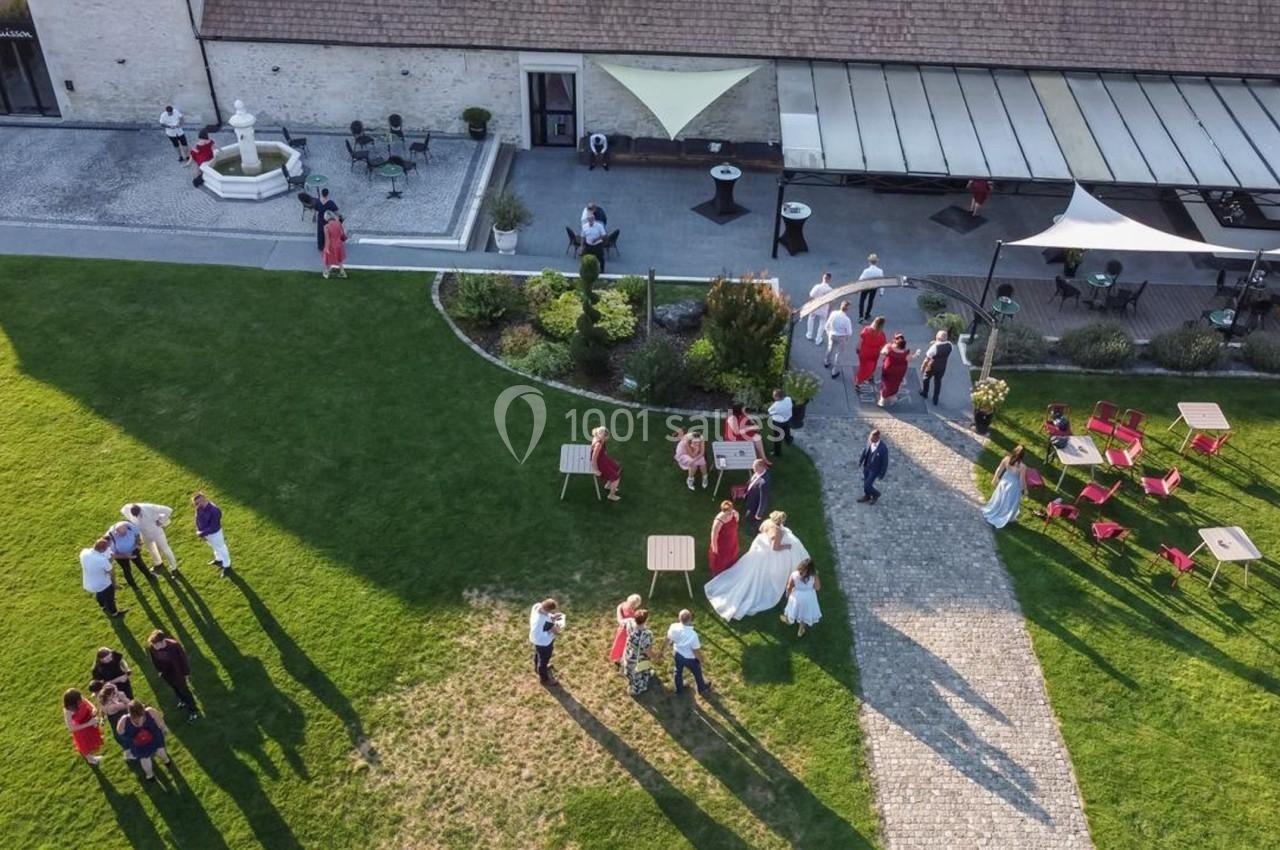 Vue aérienne d'un jardin avec des invités rassemblés lors d'une réception en plein air près d'un bâtiment.