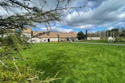 Un couple en tenue de mariage s'embrasse dans un jardin, avec des arbres en arrière-plan.