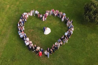 Un couple en tenue de mariage s'embrasse dans un jardin, avec des arbres en arrière-plan.