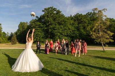 Un couple en tenue de mariage s'embrasse dans un jardin, avec des arbres en arrière-plan.