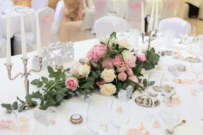 Un couple en tenue de mariage s'embrasse dans un jardin, avec des arbres en arrière-plan.