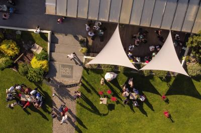 Un couple en tenue de mariage s'embrasse dans un jardin, avec des arbres en arrière-plan.