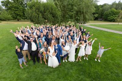 Un couple en tenue de mariage s'embrasse dans un jardin, avec des arbres en arrière-plan.