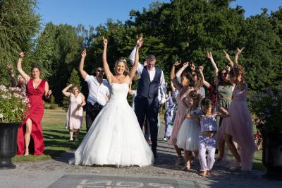 Un couple en tenue de mariage s'embrasse dans un jardin, avec des arbres en arrière-plan.