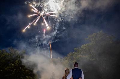 Un couple en tenue de mariage s'embrasse dans un jardin, avec des arbres en arrière-plan.