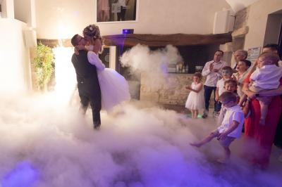 Un couple en tenue de mariage s'embrasse dans un jardin, avec des arbres en arrière-plan.