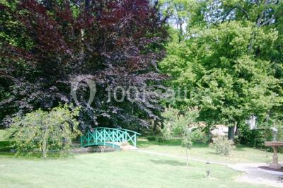 Lit avec baldaquin blanc, table de chevet en bois avec lampe en cristal, bougie et livres posés dessus.