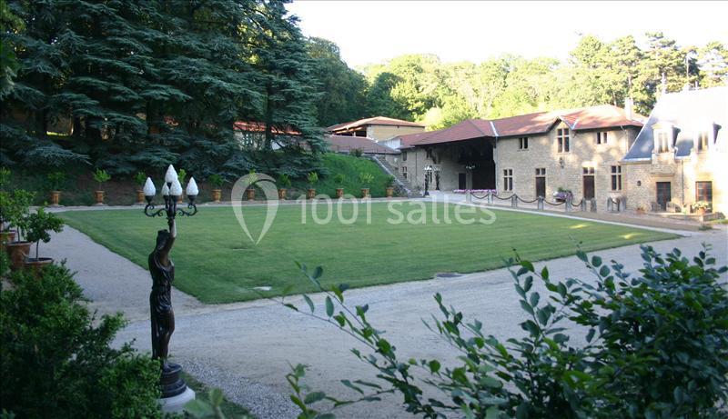 Cour intérieure avec pelouse centrale, lampadaire en fer forgé, bâtiments en pierre et arbres en arrière-plan.