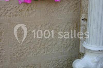 Lit avec baldaquin blanc, table de chevet en bois avec lampe en cristal, bougie et livres posés dessus.