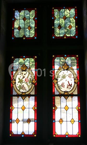 Vitrail coloré avec motifs floraux et géométriques, laissant passer la lumière à travers des panneaux ornés.