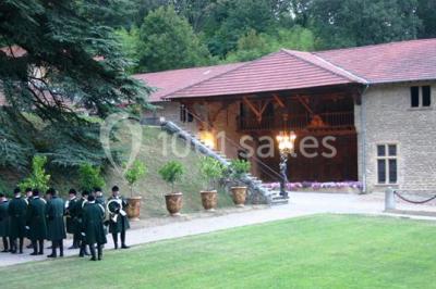 Lit avec baldaquin blanc, table de chevet en bois avec lampe en cristal, bougie et livres posés dessus.
