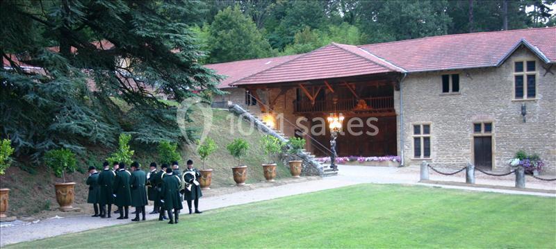 Un groupe de personnes en tenue traditionnelle discute devant un bâtiment en pierre entouré de verdure.