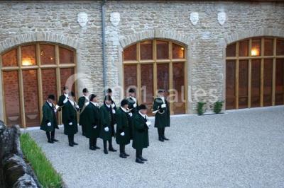 Lit avec baldaquin blanc, table de chevet en bois avec lampe en cristal, bougie et livres posés dessus.