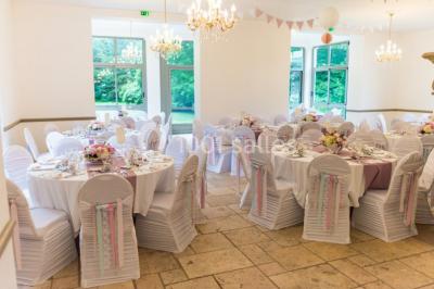Disposition de chaises blanches en extérieur autour d'une allée menant à une petite scène sous une tente blanche.