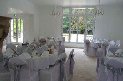 Disposition de chaises blanches en extérieur autour d'une allée menant à une petite scène sous une tente blanche.