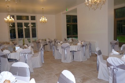 Disposition de chaises blanches en extérieur autour d'une allée menant à une petite scène sous une tente blanche.