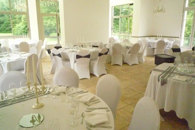 Disposition de chaises blanches en extérieur autour d'une allée menant à une petite scène sous une tente blanche.