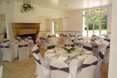 Disposition de chaises blanches en extérieur autour d'une allée menant à une petite scène sous une tente blanche.