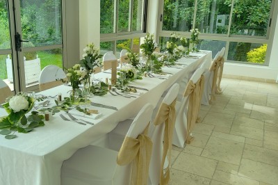 Disposition de chaises blanches en extérieur autour d'une allée menant à une petite scène sous une tente blanche.