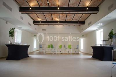 Vue aérienne d'un bâtiment en forme de cour rectangulaire avec des toits en tuiles, entouré de champs et d'arbres.