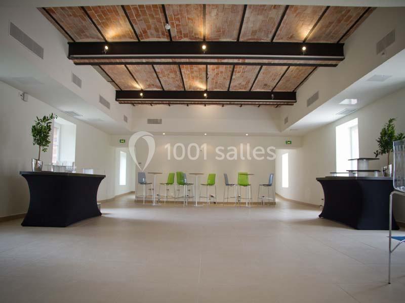 Salle lumineuse avec plafond en briques apparentes, tables hautes, chaises colorées et mobilier noir moderne.