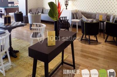 Vue aérienne d'un bâtiment en forme de cour rectangulaire avec des toits en tuiles, entouré de champs et d'arbres.