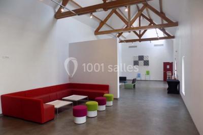 Vue aérienne d'un bâtiment en forme de cour rectangulaire avec des toits en tuiles, entouré de champs et d'arbres.