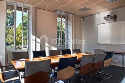 Vue aérienne d'un bâtiment en forme de cour rectangulaire avec des toits en tuiles, entouré de champs et d'arbres.