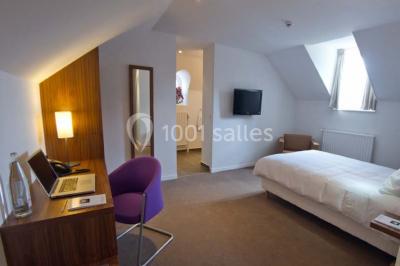 Vue aérienne d'un bâtiment en forme de cour rectangulaire avec des toits en tuiles, entouré de champs et d'arbres.