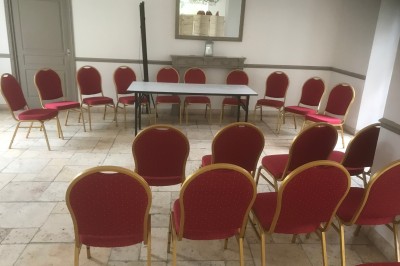 Mobilier de jardin en rotin avec coussins, disposé dans une véranda lumineuse avec des plantes en pot.