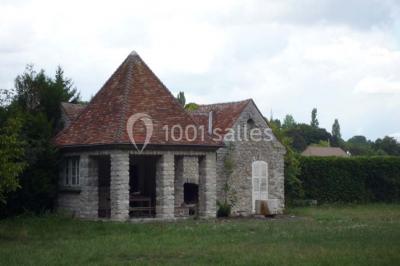 Mobilier de jardin en rotin avec coussins, disposé dans une véranda lumineuse avec des plantes en pot.