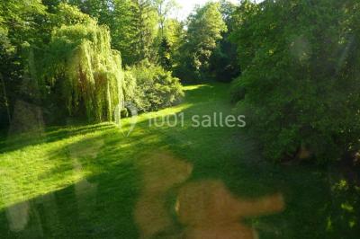 Mobilier de jardin en rotin avec coussins, disposé dans une véranda lumineuse avec des plantes en pot.