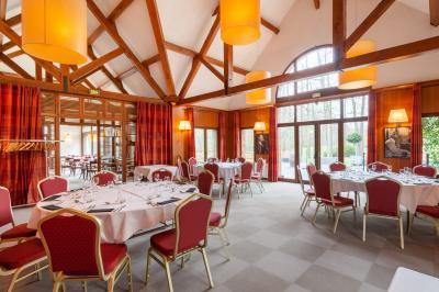 Maison en bois éclairée la nuit, entourée d'arbres illuminés, sous un ciel nuageux avec la lune visible.