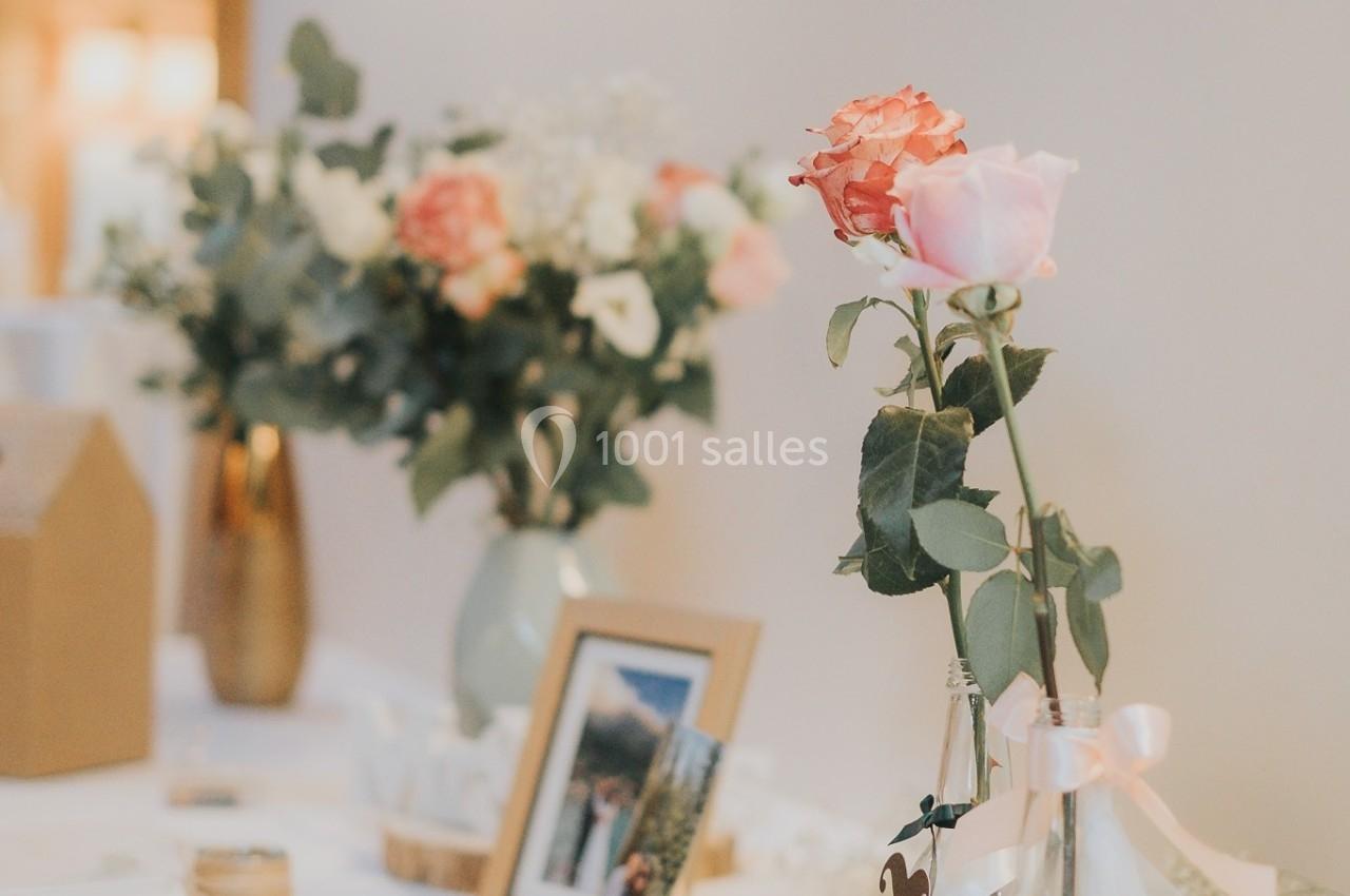 Décoration de table avec roses, eucalyptus, bougies et cadre photo, dans une ambiance lumineuse et élégante.