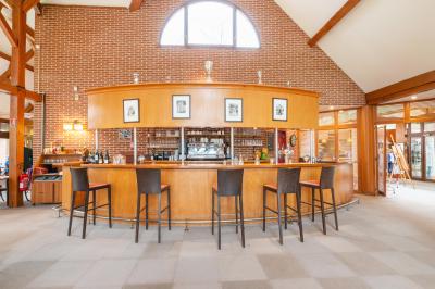 Maison en bois éclairée la nuit, entourée d'arbres illuminés, sous un ciel nuageux avec la lune visible.