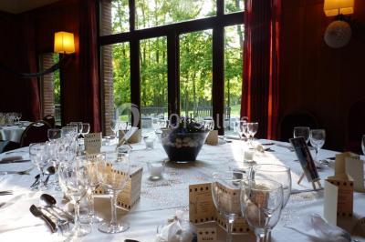 Maison en bois éclairée la nuit, entourée d'arbres illuminés, sous un ciel nuageux avec la lune visible.
