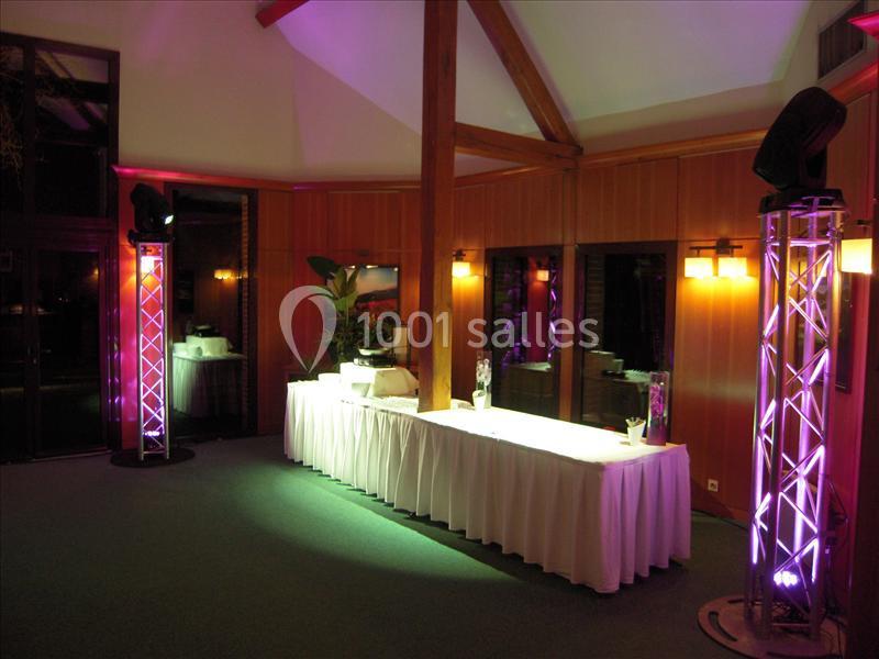 Salle de réception avec table drapée blanche, éclairages colorés et structures lumineuses en métal.