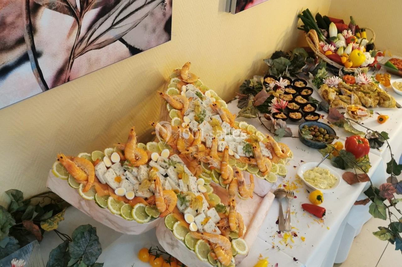 Buffet décoratif avec fruits de mer, légumes, et plats variés disposés sur une table ornée de feuilles et fleurs.
