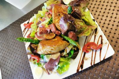 Assiette de salade garnie de magret de canard, asperges, figues, tomates séchées et filet de sauce balsamique.