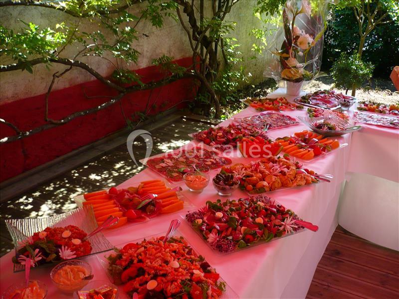 Buffet coloré disposé sur des tables en extérieur, avec divers plats et décorations sous un éclairage naturel.