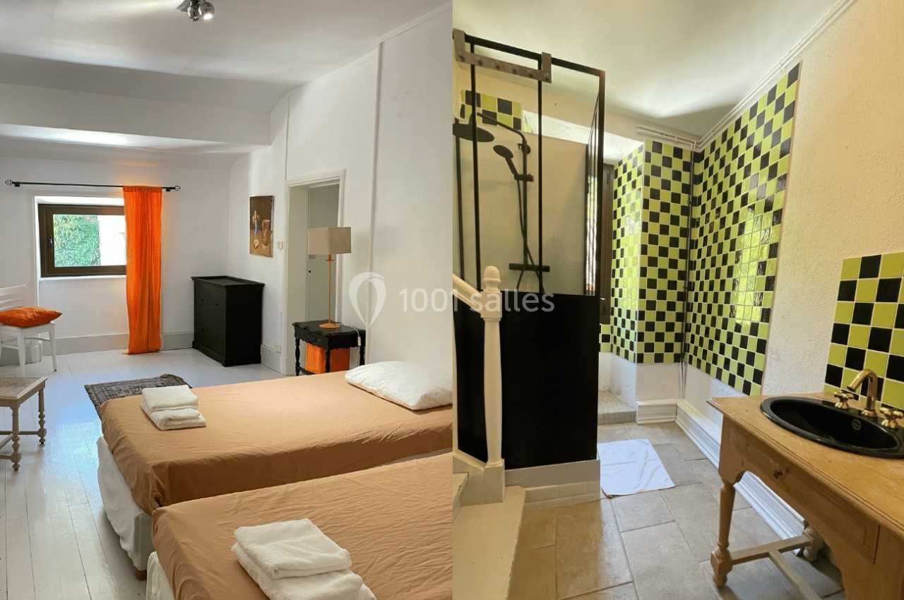 Chambre avec deux lits simples, fenêtre lumineuse, et salle de bain attenante avec douche et carrelage noir et jaune.