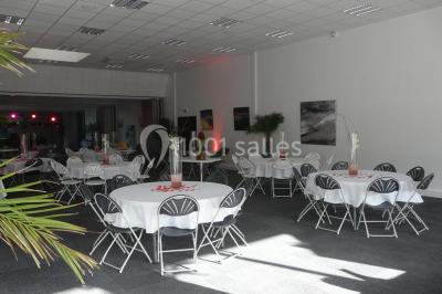 Table décorée avec un vase, des pétales rouges et des plantes en pot dans une salle lumineuse.
